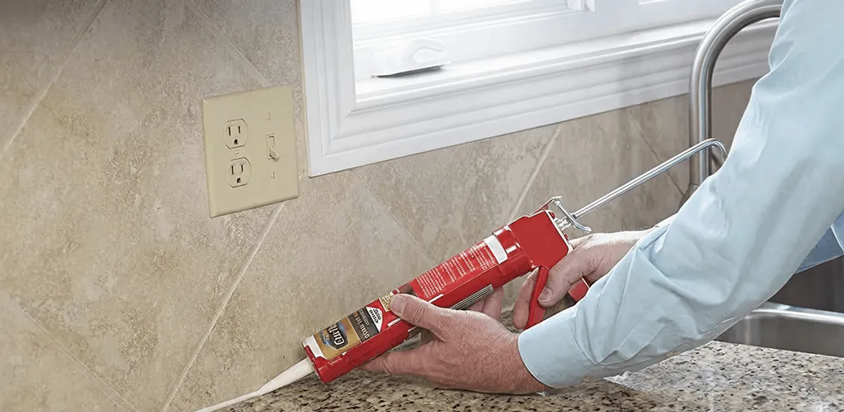 Handyman applying caulk along a kitchen backsplash and countertop seam in Lincoln, NE